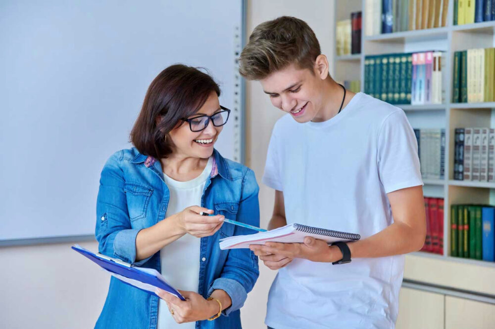 teen-boy-speaking-with-female-counselor-holding-a-notebook